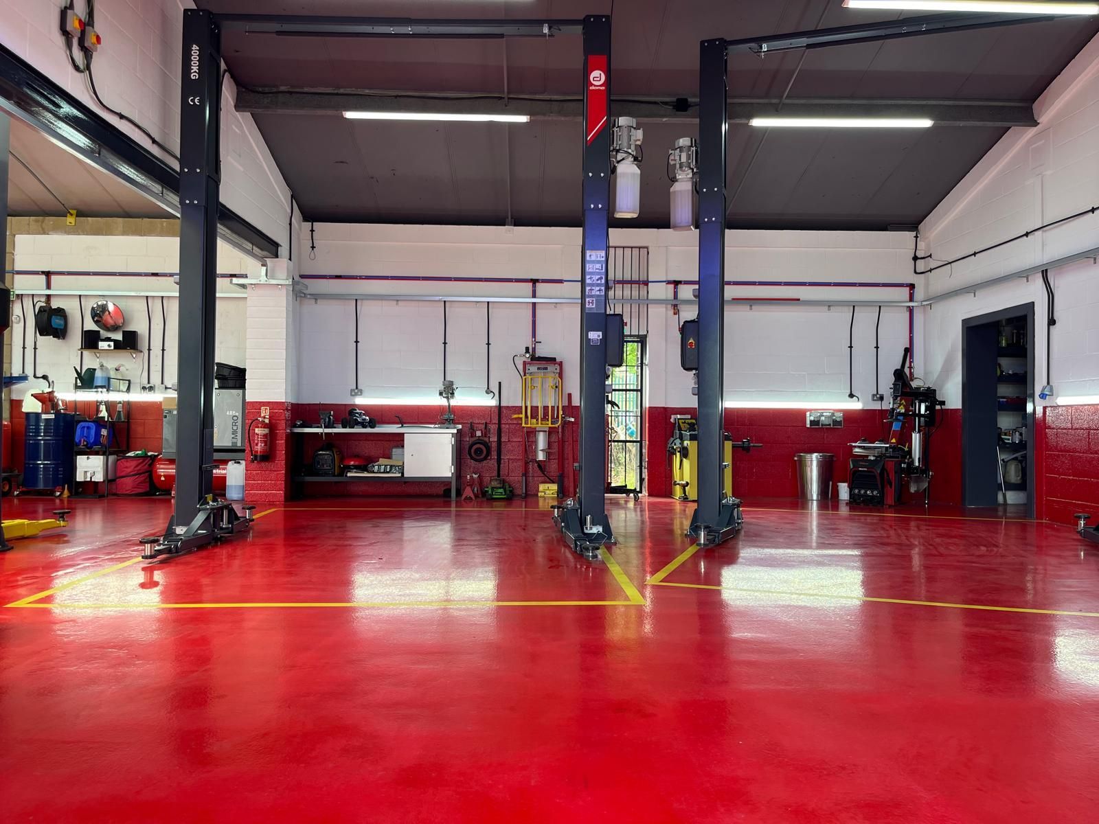 A garage with a red floor and two lifts in it.