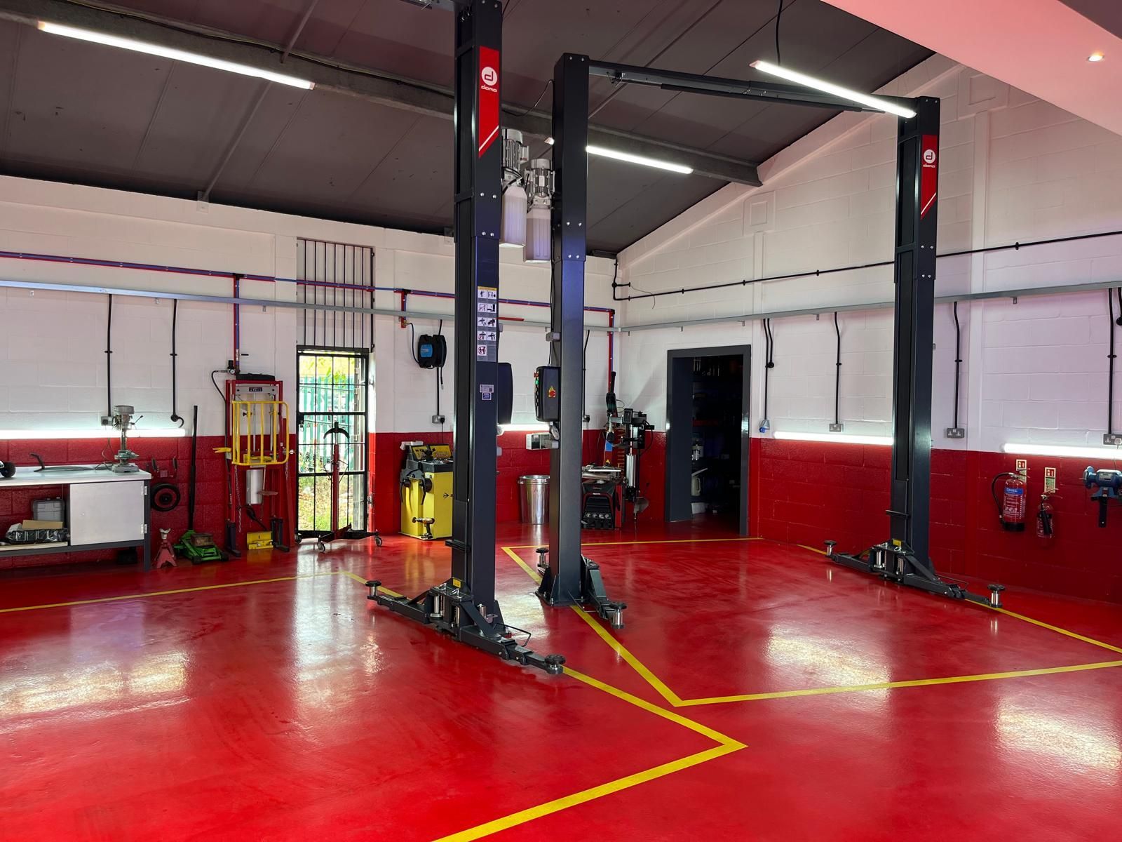 A garage with two lifts in it and a red floor.