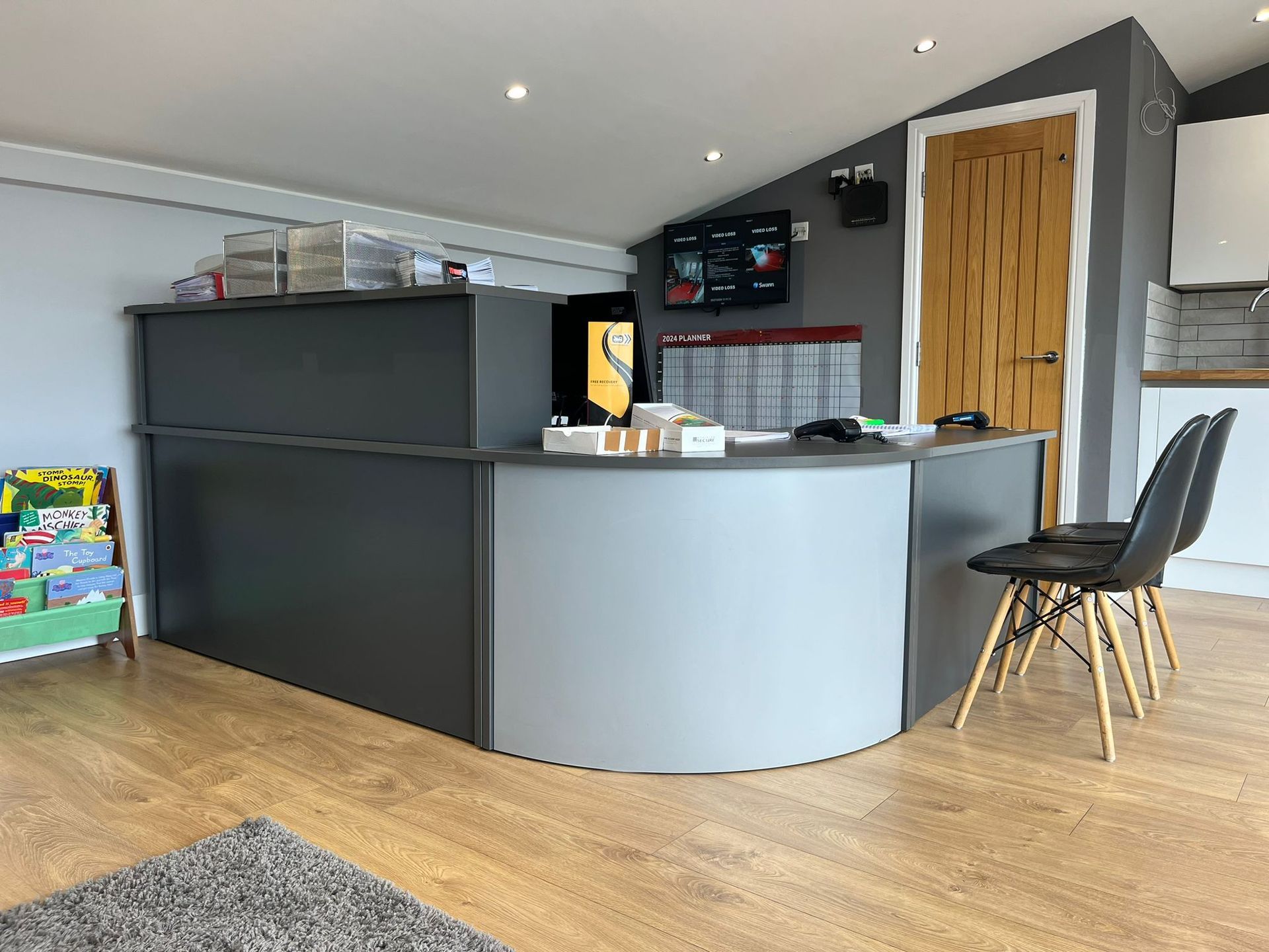 A reception desk in a room with wooden floors and chairs.