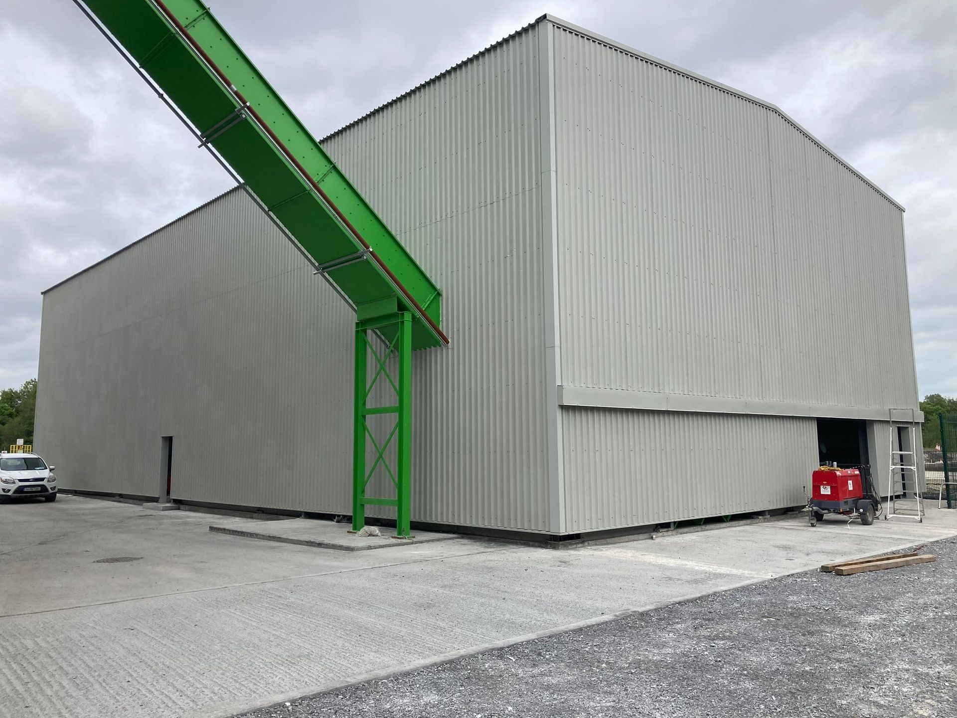 A large building with a green conveyor belt attached to it