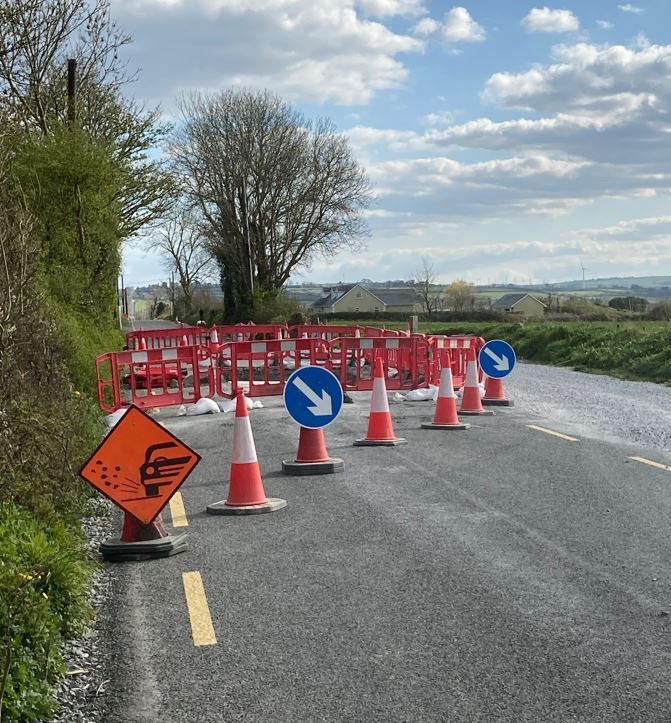 A row of traffic cones are lined up on the side of a road