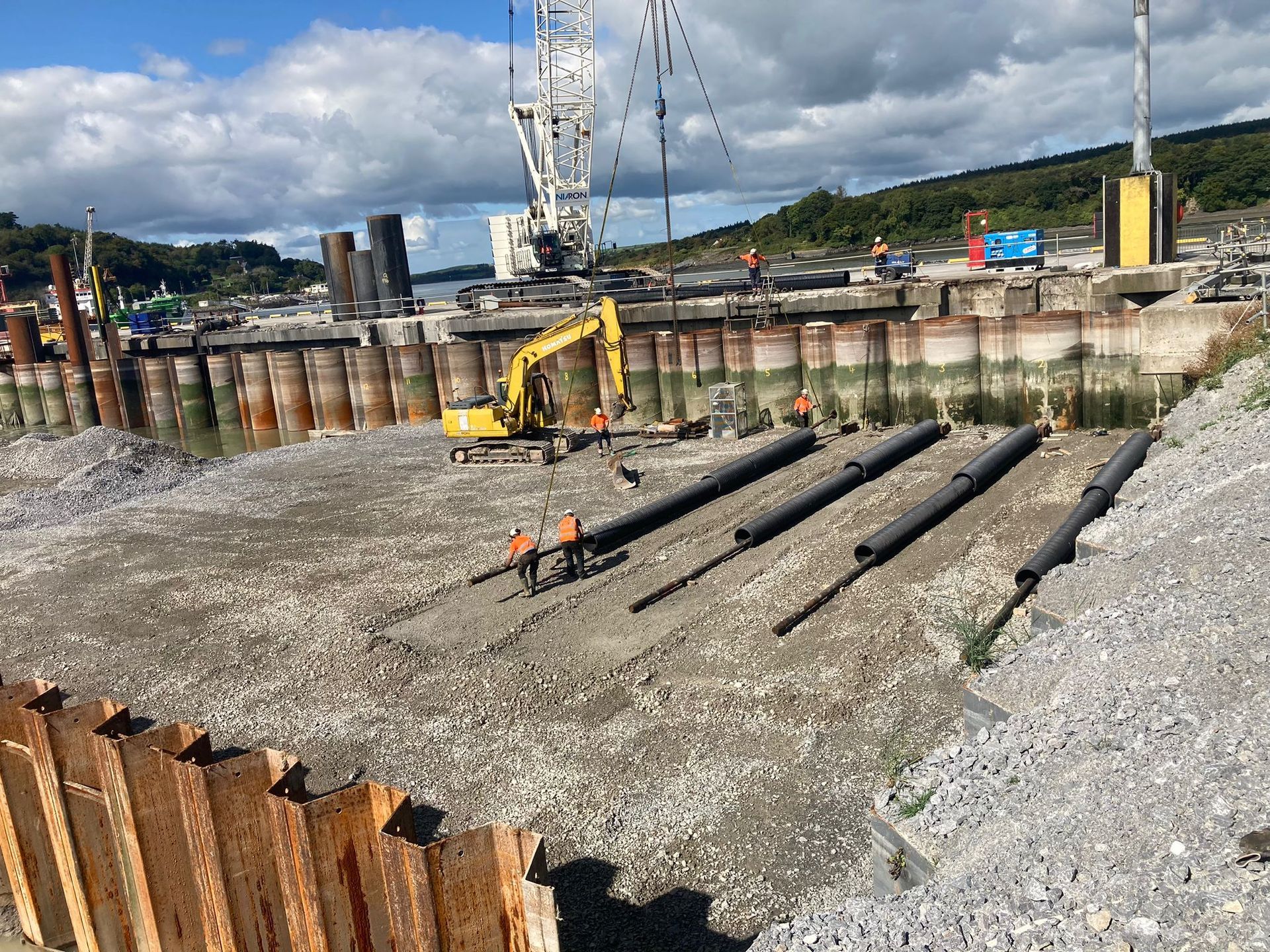 A construction site with a lot of pipes and a crane in the background
