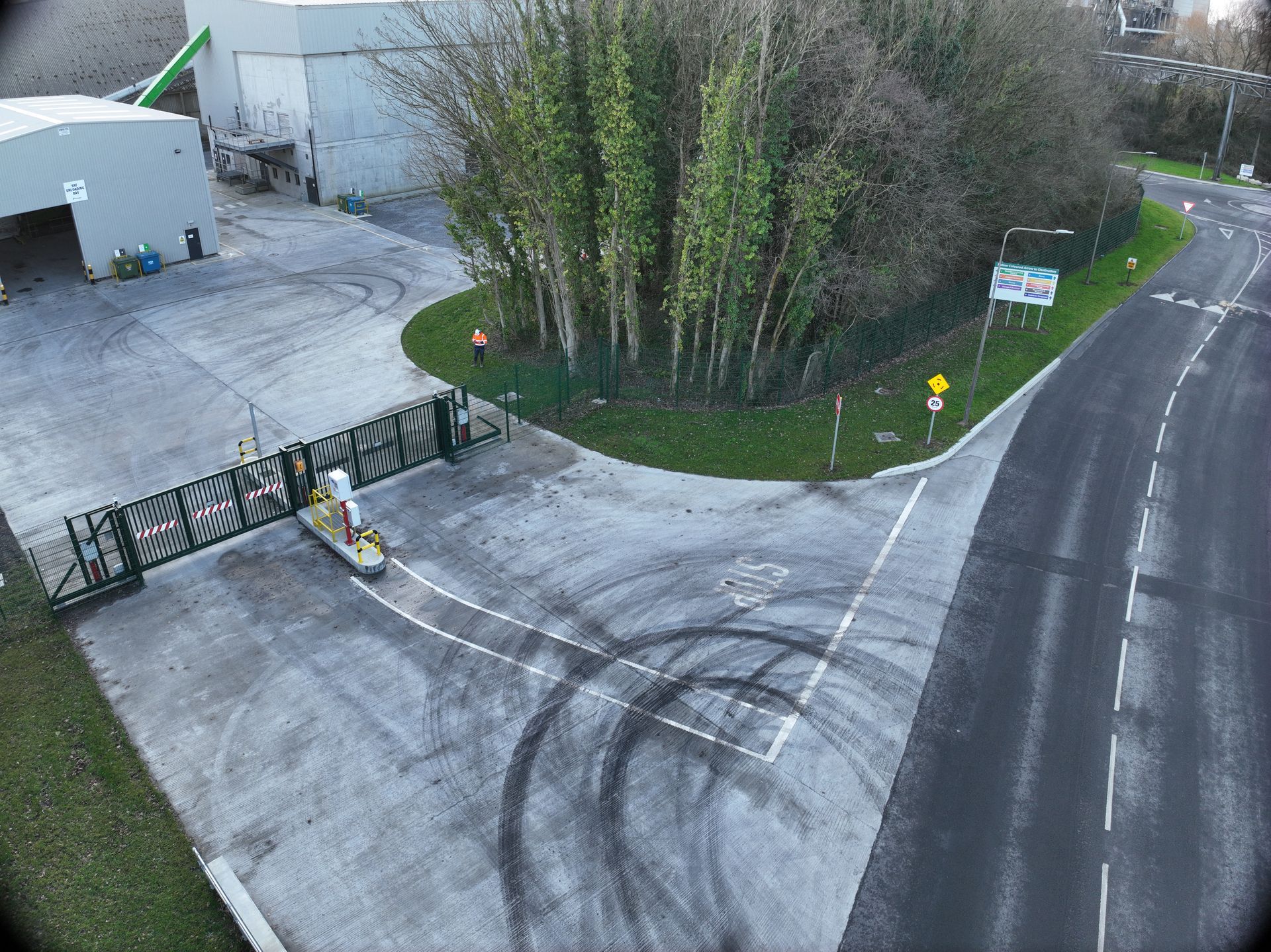 An aerial view of a road with a fence and a building in the background