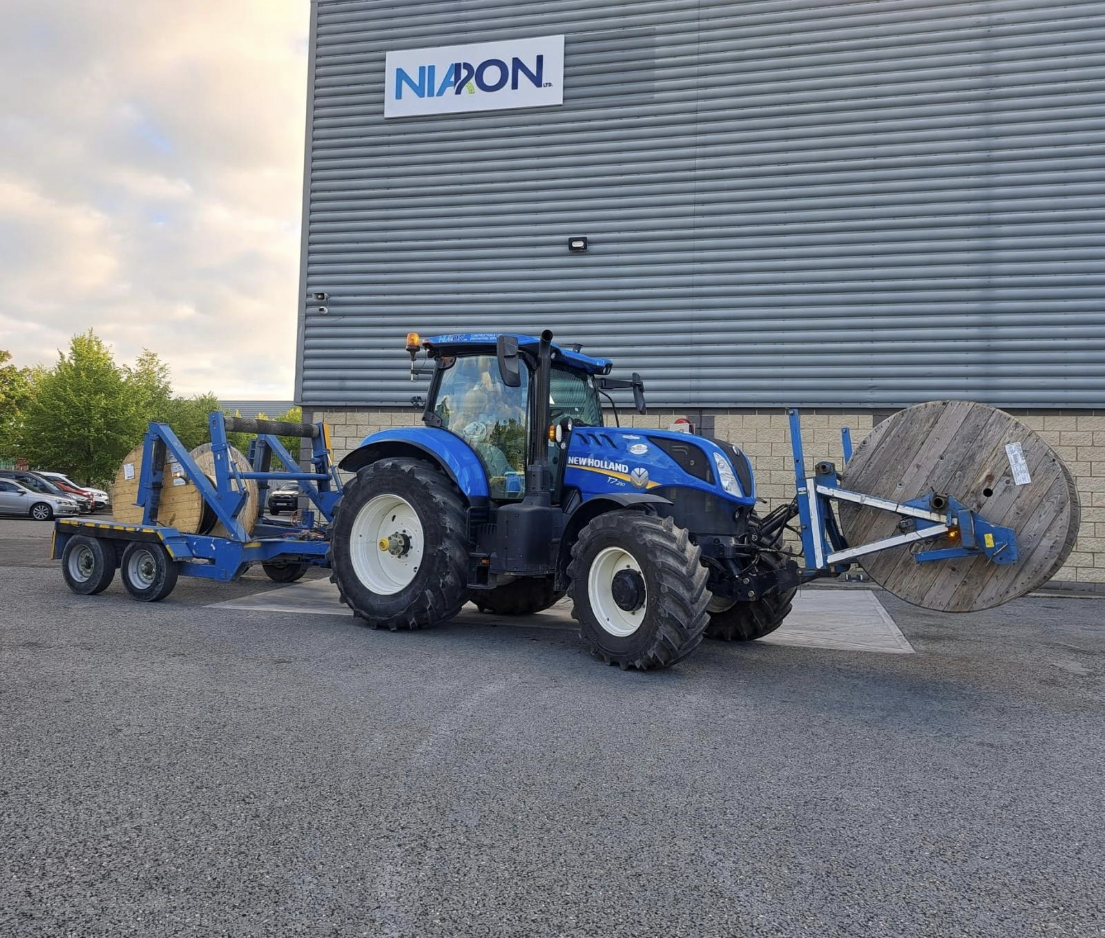 A blue tractor is parked in front of a building that says nlpon