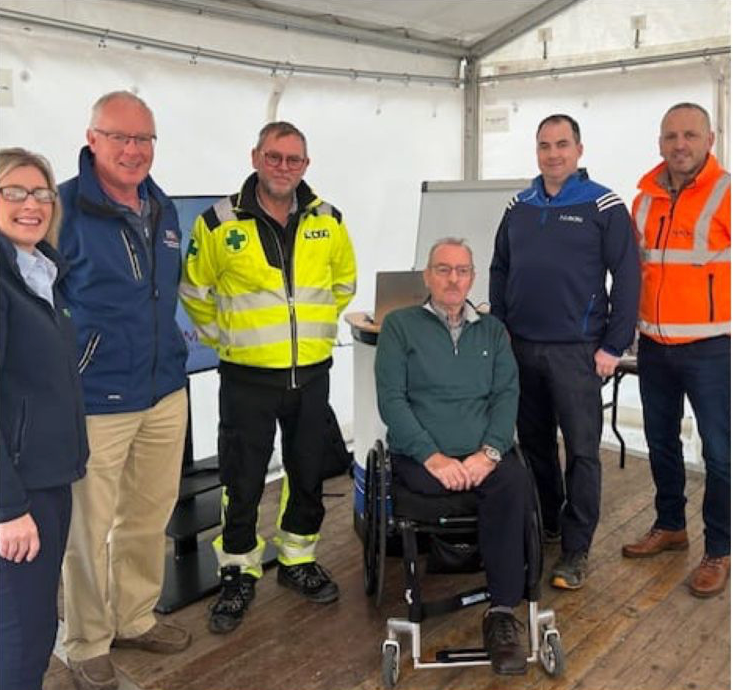 A man in a wheelchair is surrounded by other people