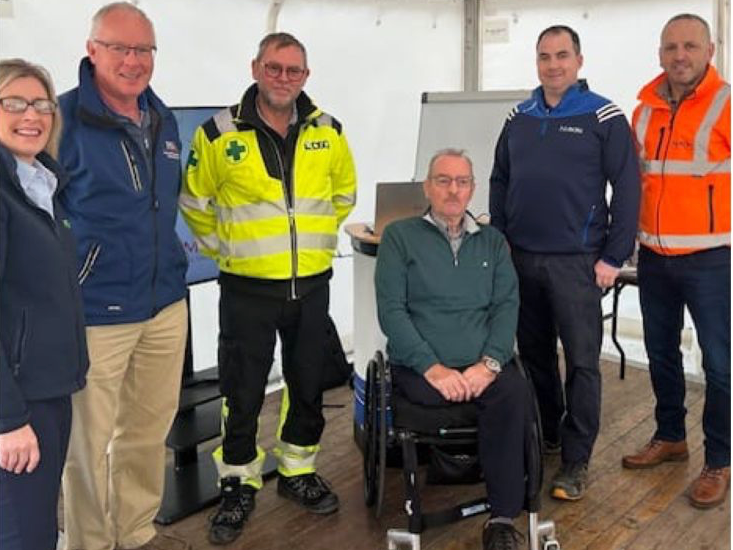 A group of people standing around a man in a wheelchair.