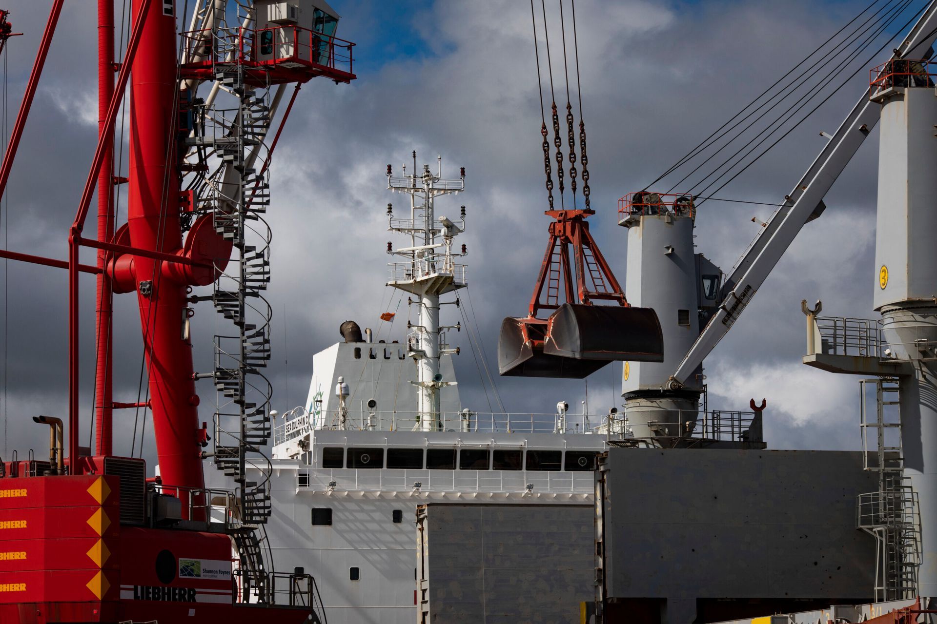A large ship is being loaded with cargo by a large crane