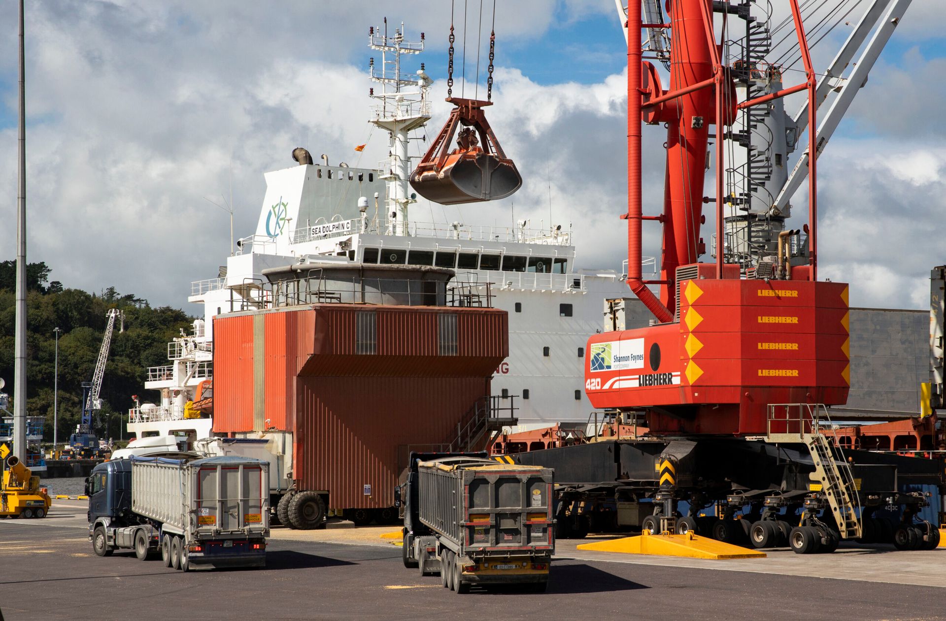 A large red crane is lifting a large ship