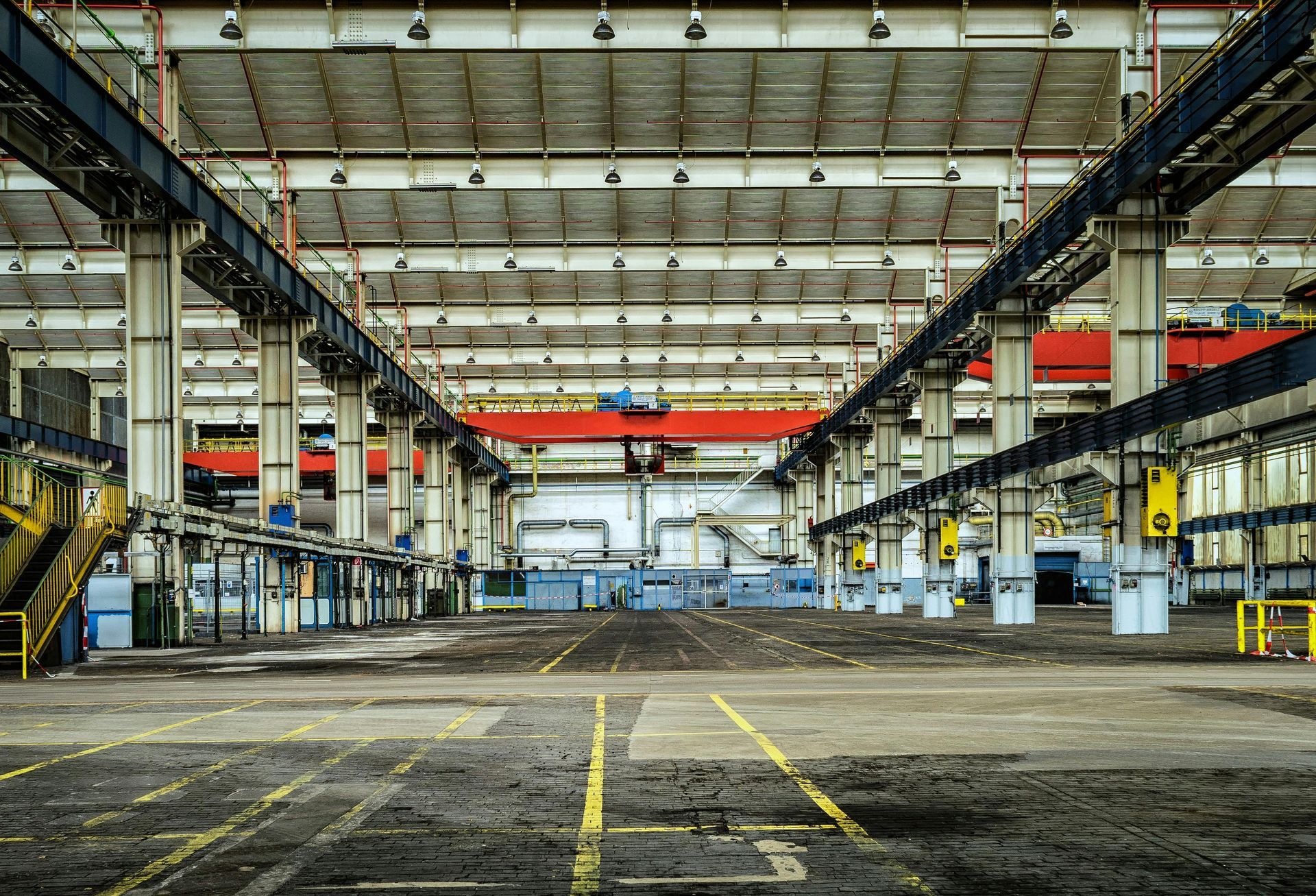 An empty factory with a red crane in the middle