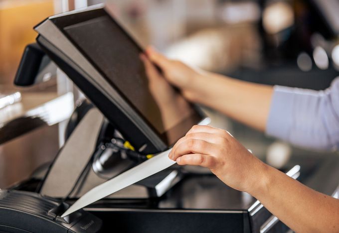 Person's hands interacting with a touchscreen device, likely a point-of-sale system.