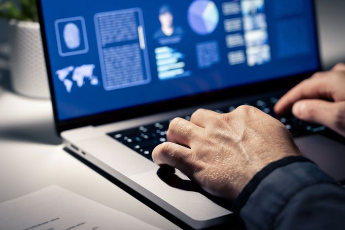 Hands typing on a laptop displaying a user interface with biometric data. White desk, indoor setting.