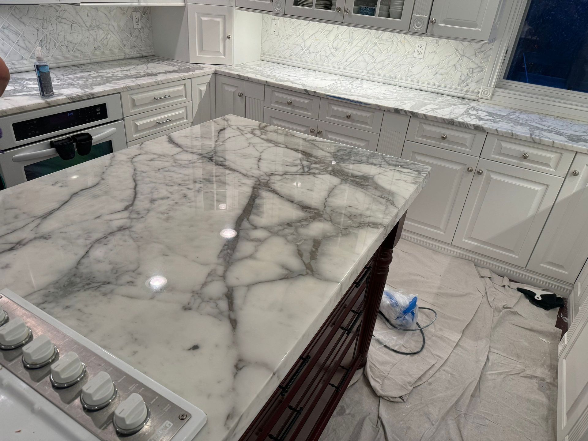 Kitchen with white cabinets, marble countertops, and a dark wood island.