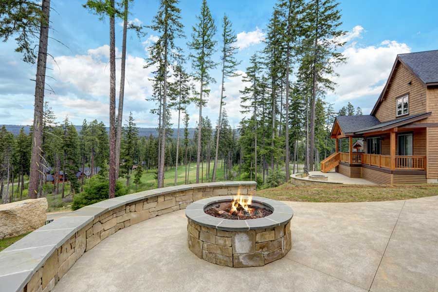 There is a fire pit in the middle of the patio in front of a house.