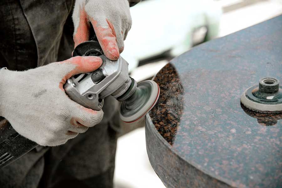 A man is using a grinder to polish a stone.