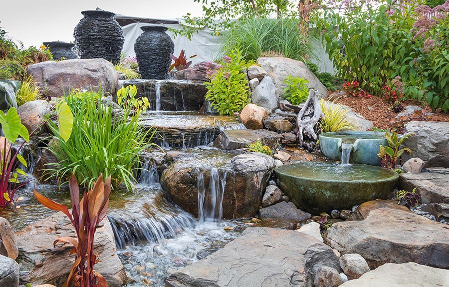 A waterfall is surrounded by rocks and plants in a garden.