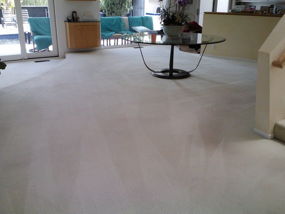 A living room with white carpet and a glass coffee table