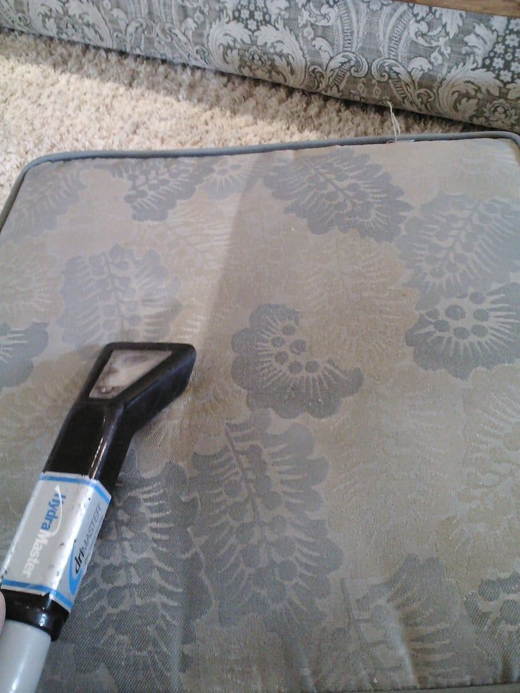 A vacuum cleaner is being used to clean a couch