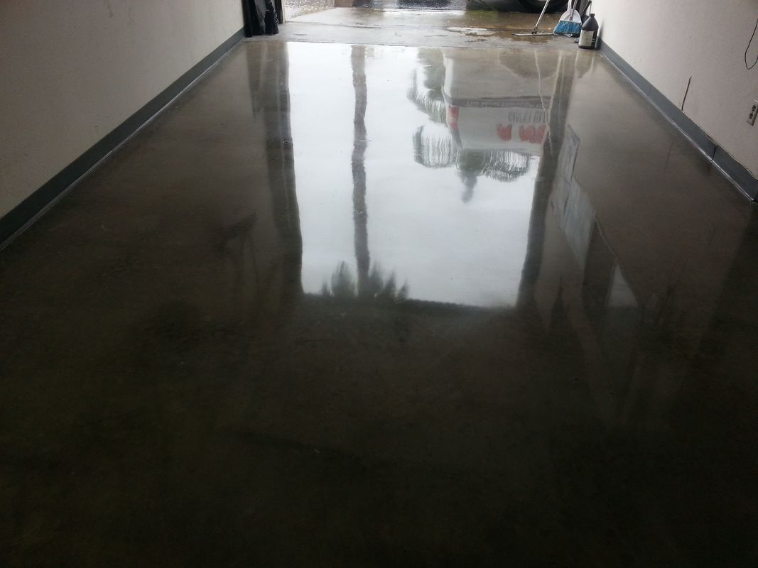 A shiny concrete floor with a reflection of a building in it.
