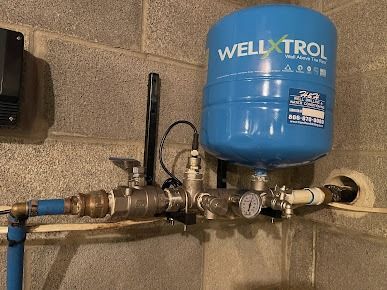 A blue water tank is attached to a brick wall.