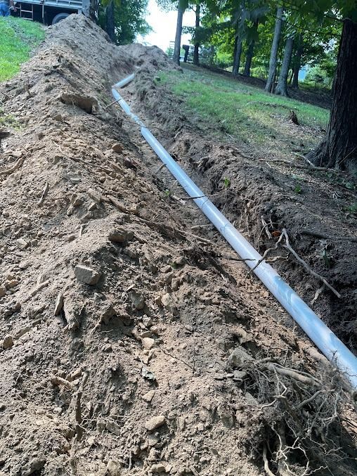 A pipe is laying in the dirt next to a pile of dirt.