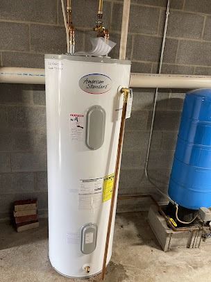 A white water heater is sitting in a basement next to a blue tank.