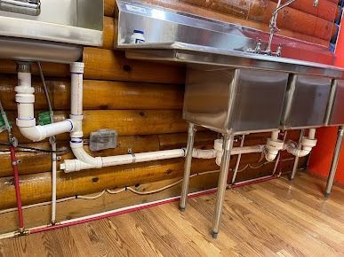 A stainless steel sink is sitting next to a wooden wall.