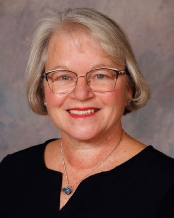 A woman wearing glasses and a black shirt smiles for the camera