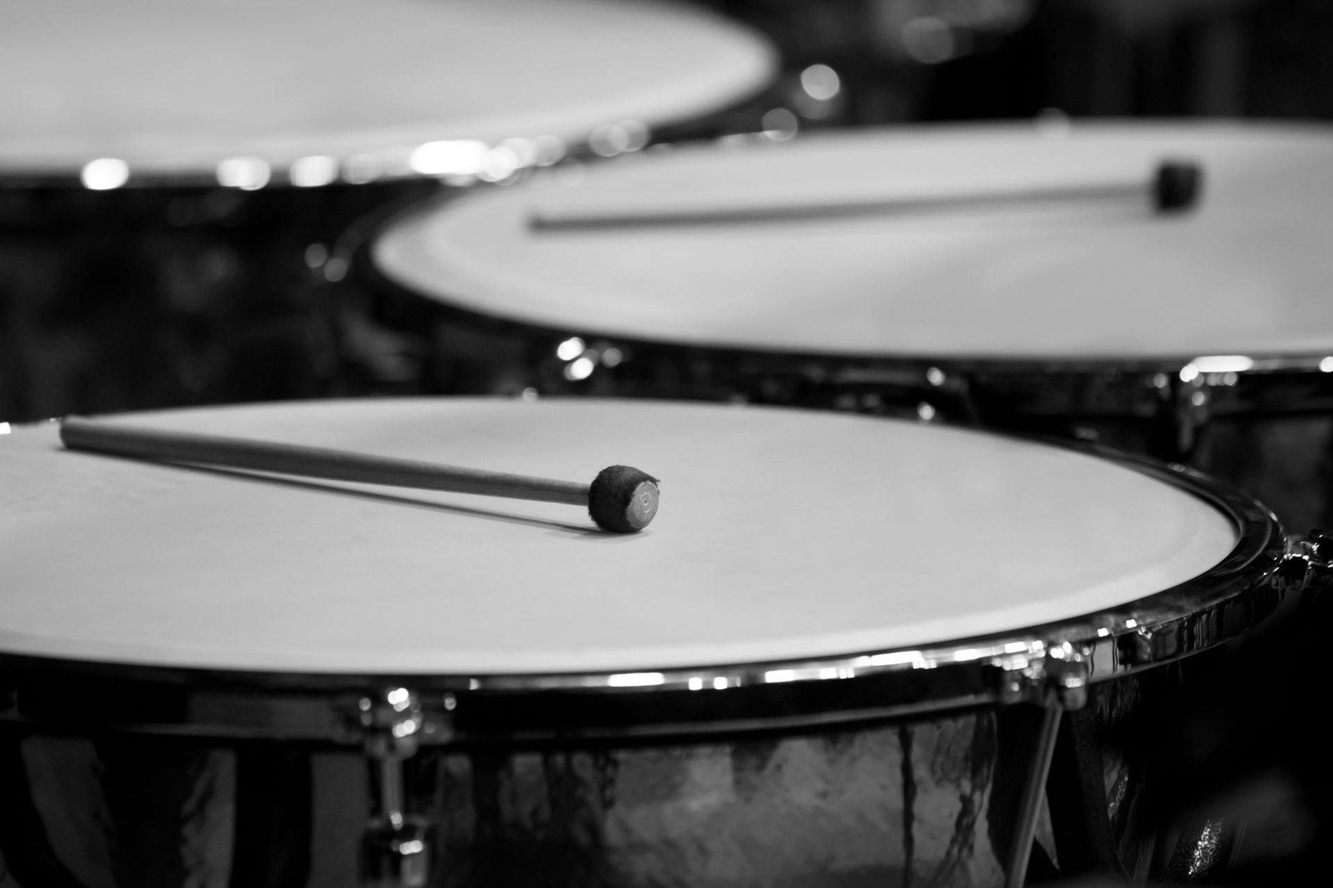 A black and white photo of a drum set with a drum stick on top.