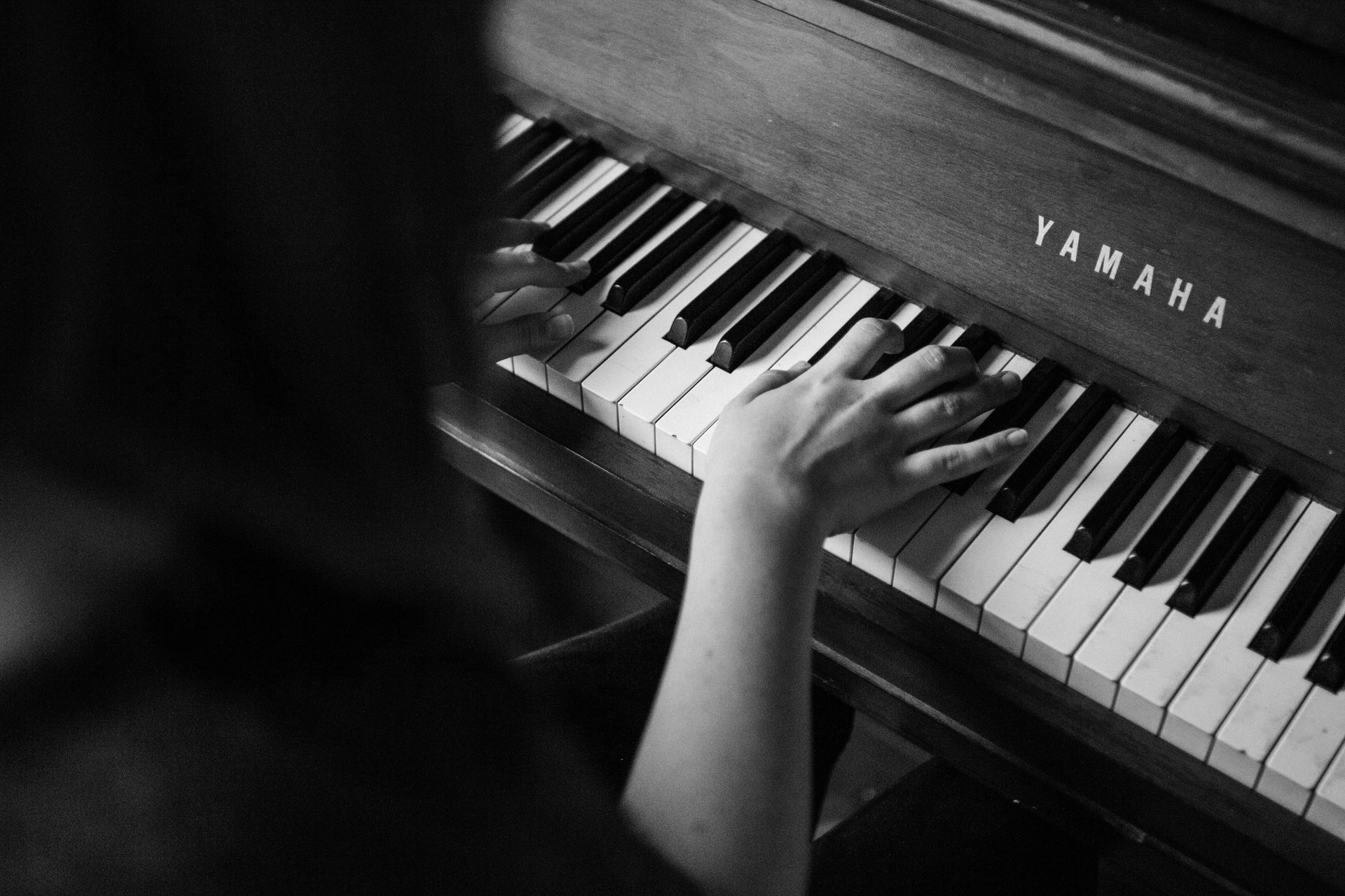 A person is playing a yamaha piano in a black and white photo