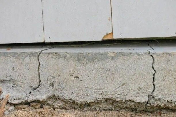House with foundation cracks caused by unstable soil conditions, needing foundation repair services.