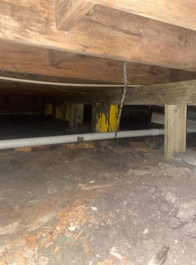 A construction worker is laying concrete with a trowel for house foundation repair.