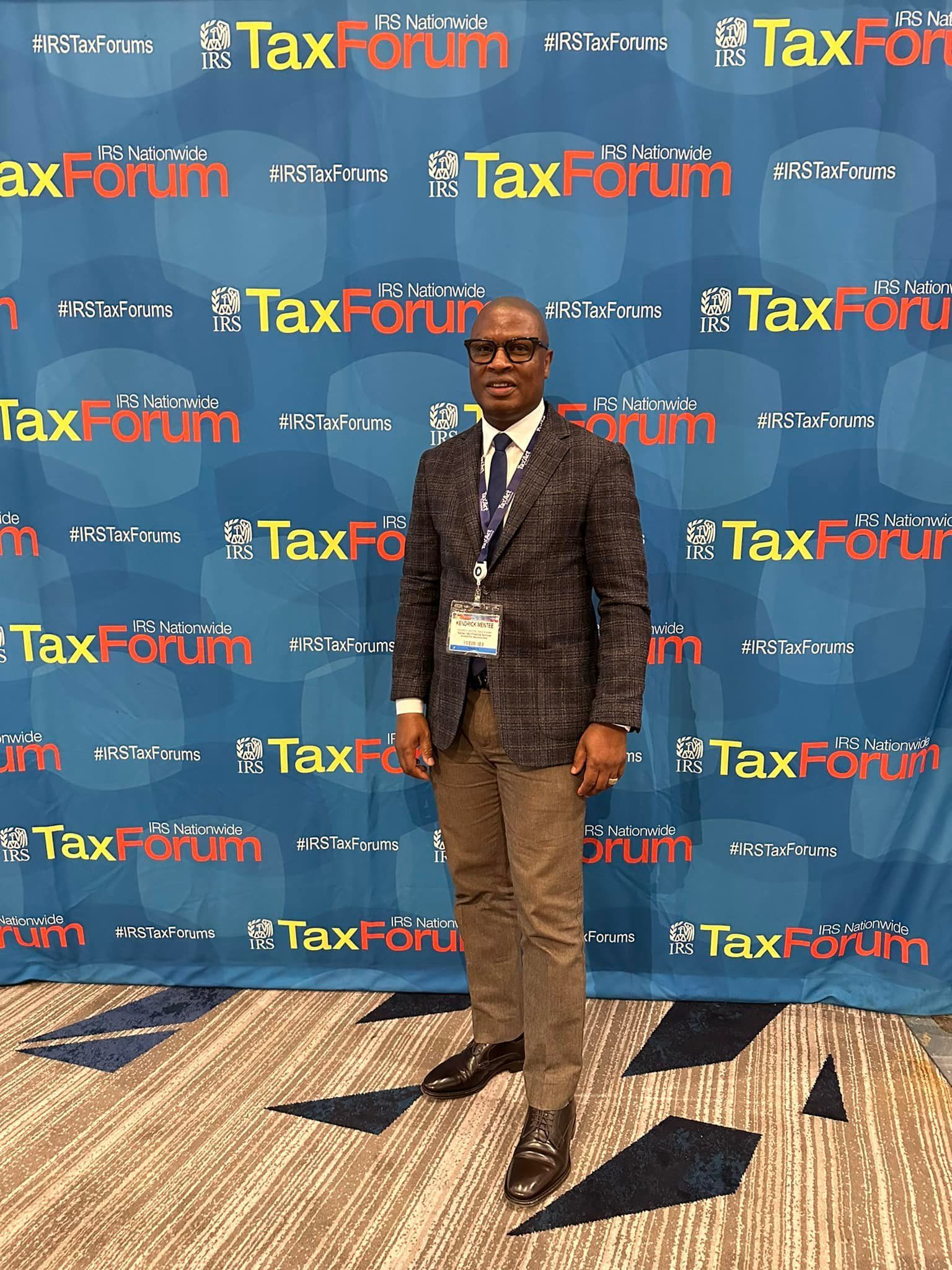 A man is sitting in a warehouse using a tablet and a cell phone.
