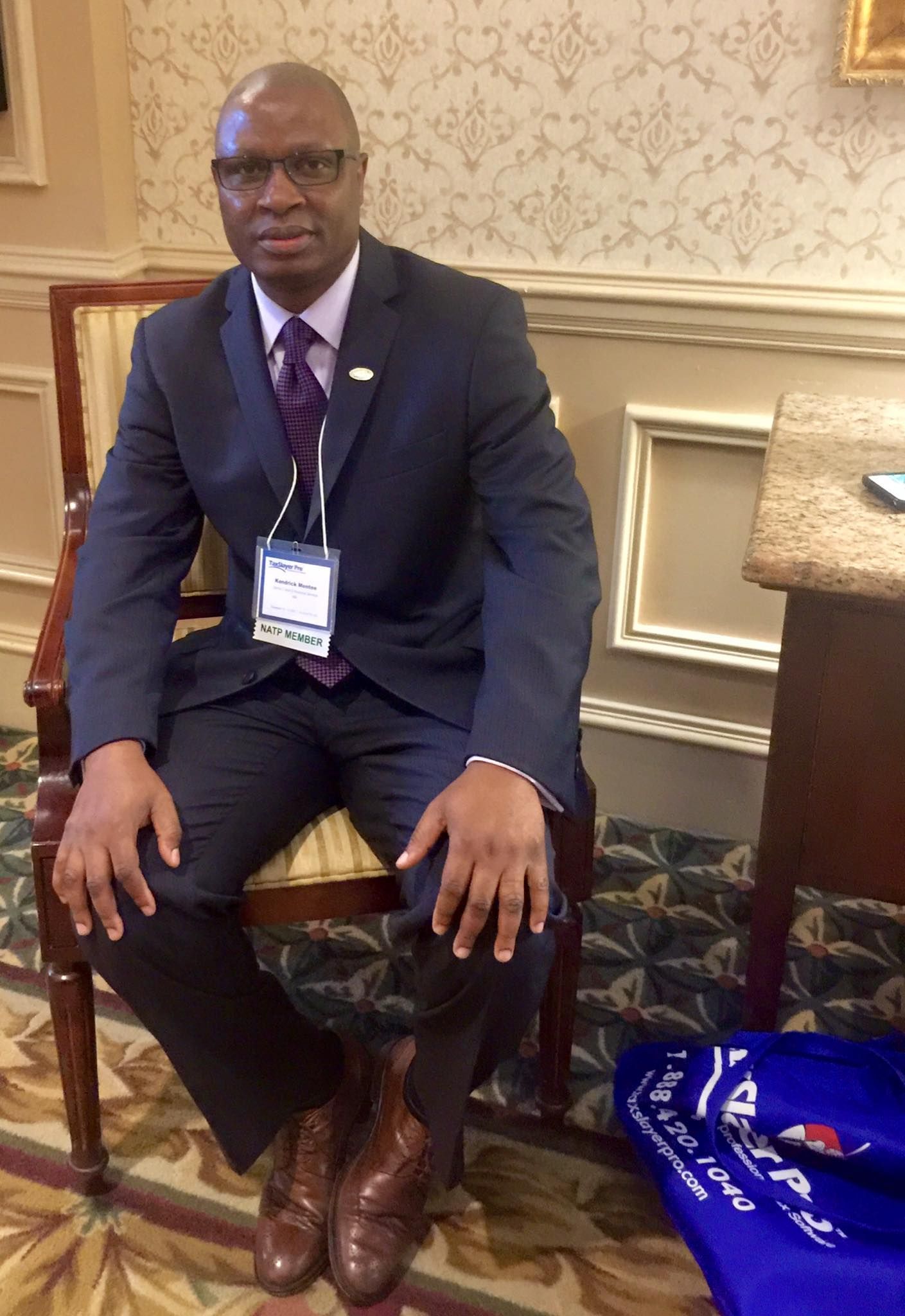 A man is kneeling down in a warehouse using a scanner and a tablet.
