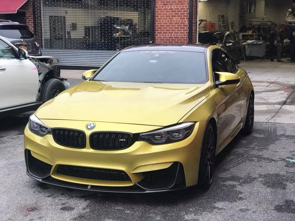 A yellow bmw m4 is parked in a parking lot.