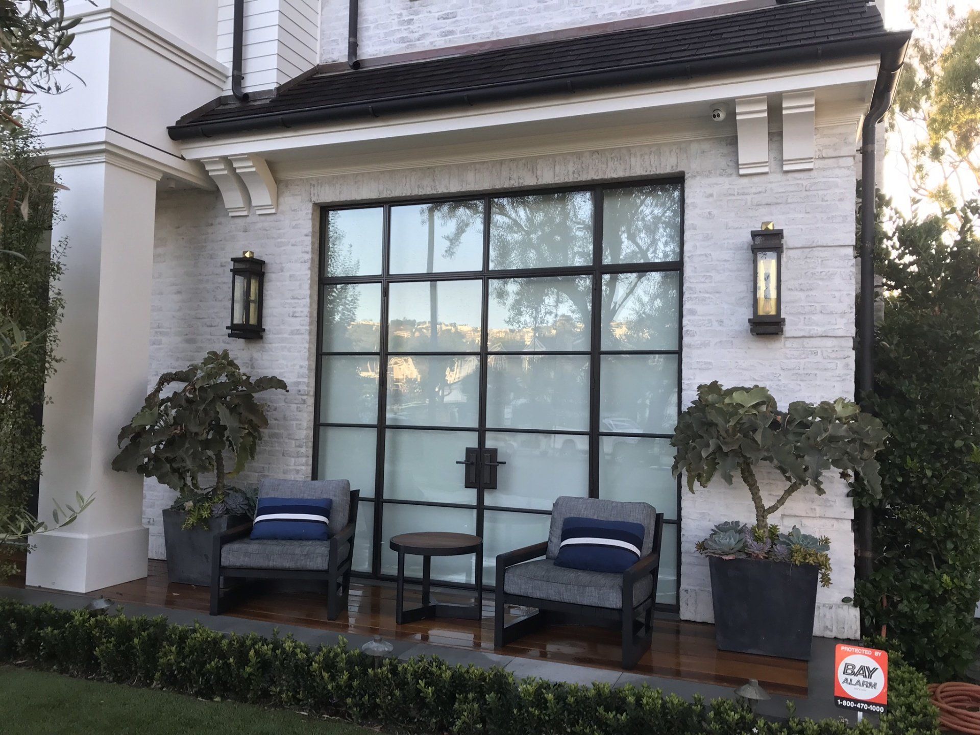 There are two chairs and a table on the porch of a house.