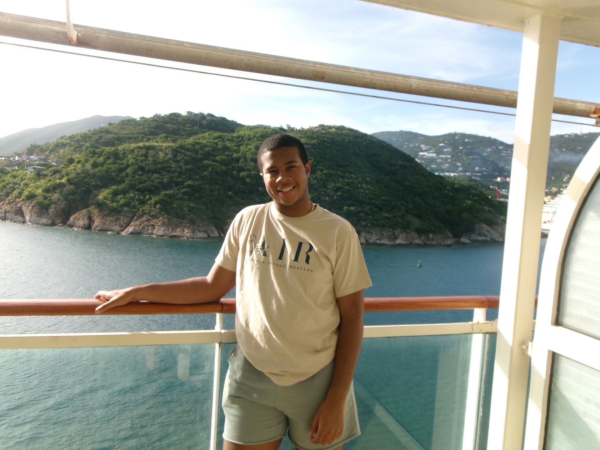 A man wearing a t-shirt that says mar is standing on a balcony overlooking the ocean