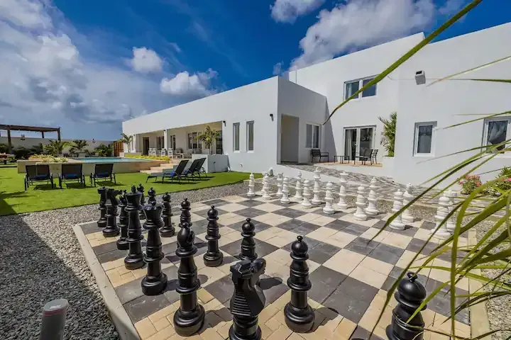 A large chess board is in front of a white building.