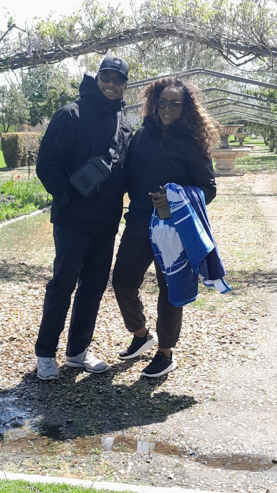 A man and a woman are standing next to each other in a park.