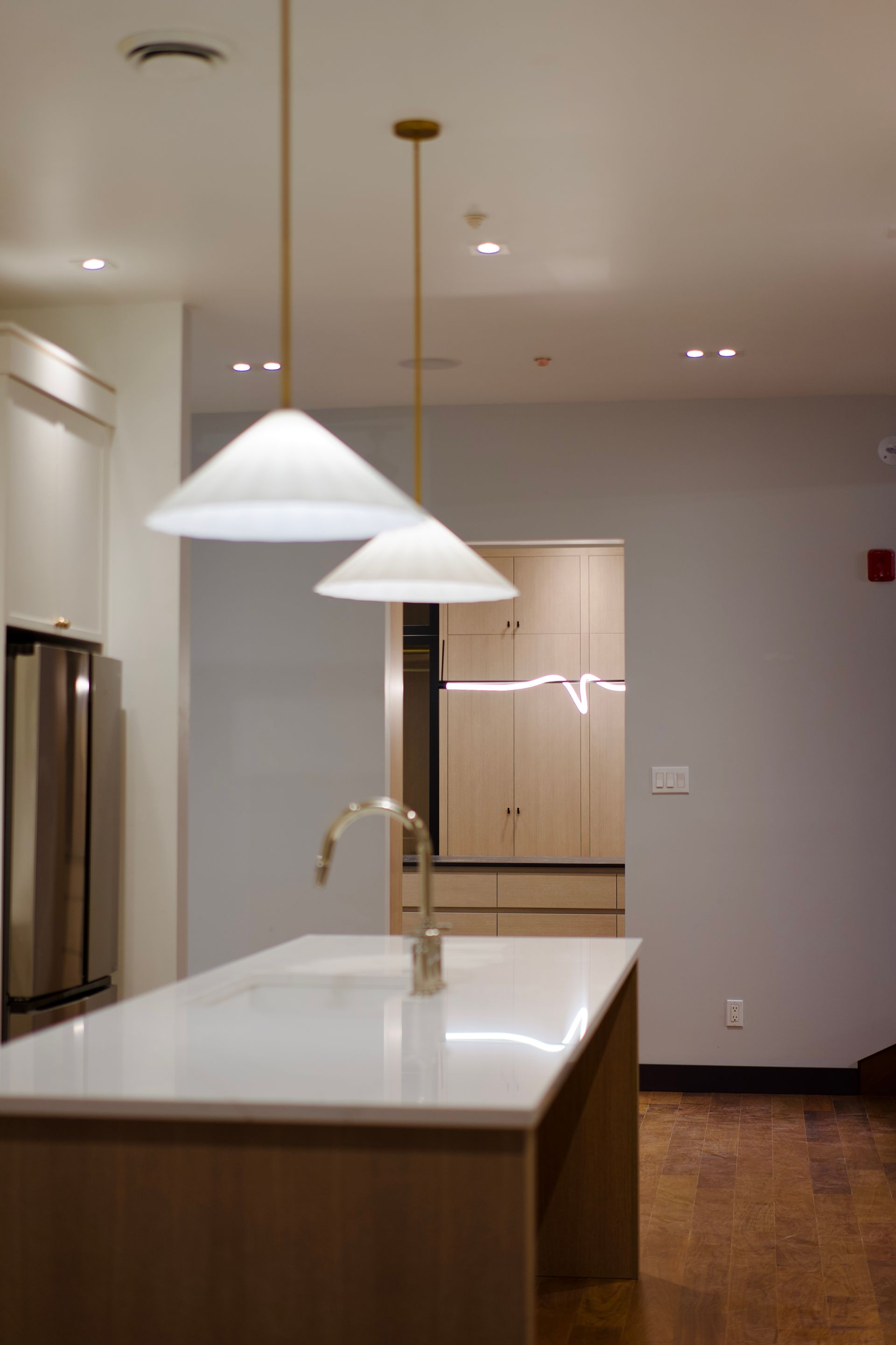 Une cuisine avec un grand îlot et deux lumières suspendues au plafond