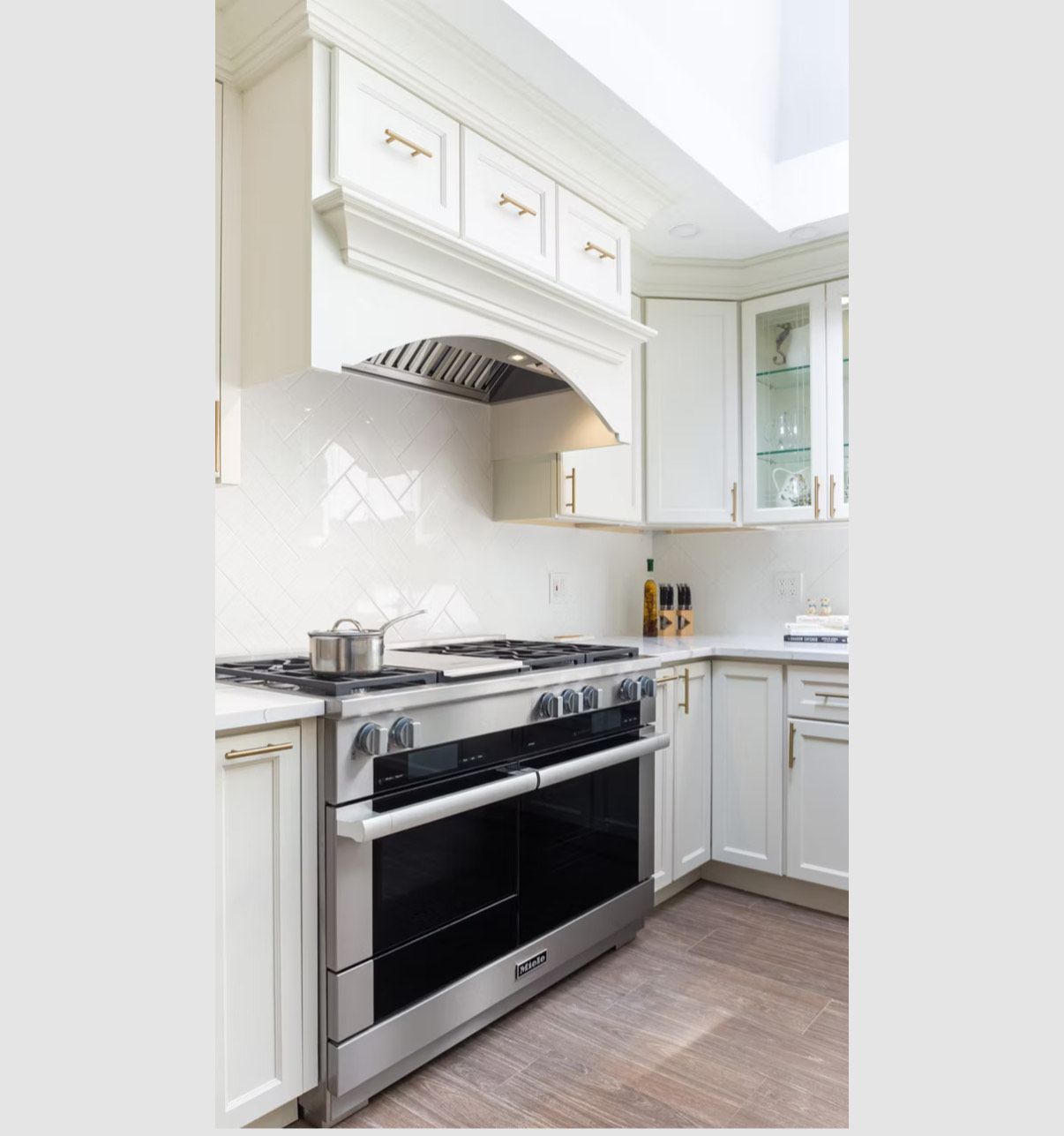 Four en acier inoxydable avec hotte aspirante et meubles blancs dans une cuisine lumineuse.