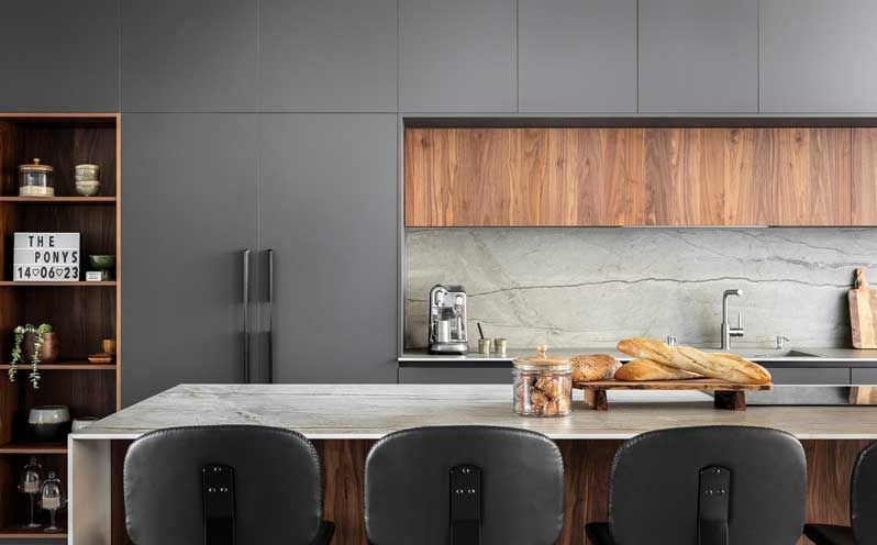 Cuisine moderne avec armoires grises, éléments en bois et coin bar.