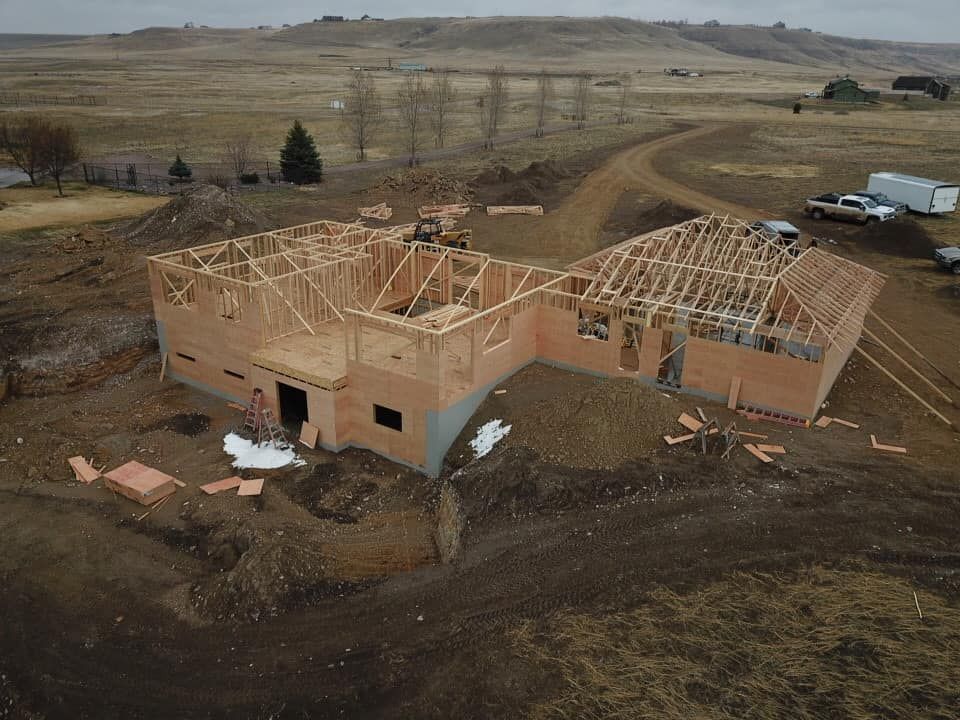 Construction site: Wooden frame of a house under construction in a rural, brown field.