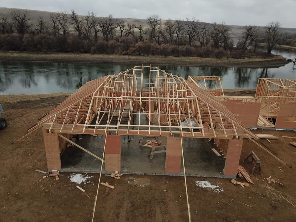 Construction of a wooden building with a curved roof frame near a river.