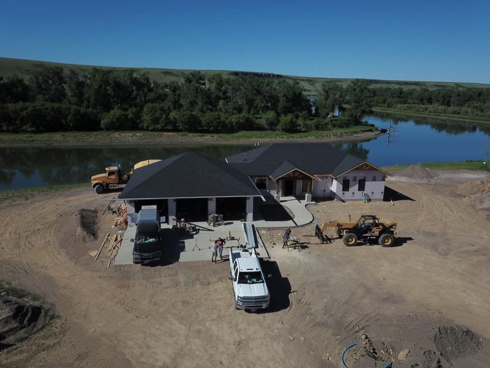 Construction site of a home with a lake and hills in the background.