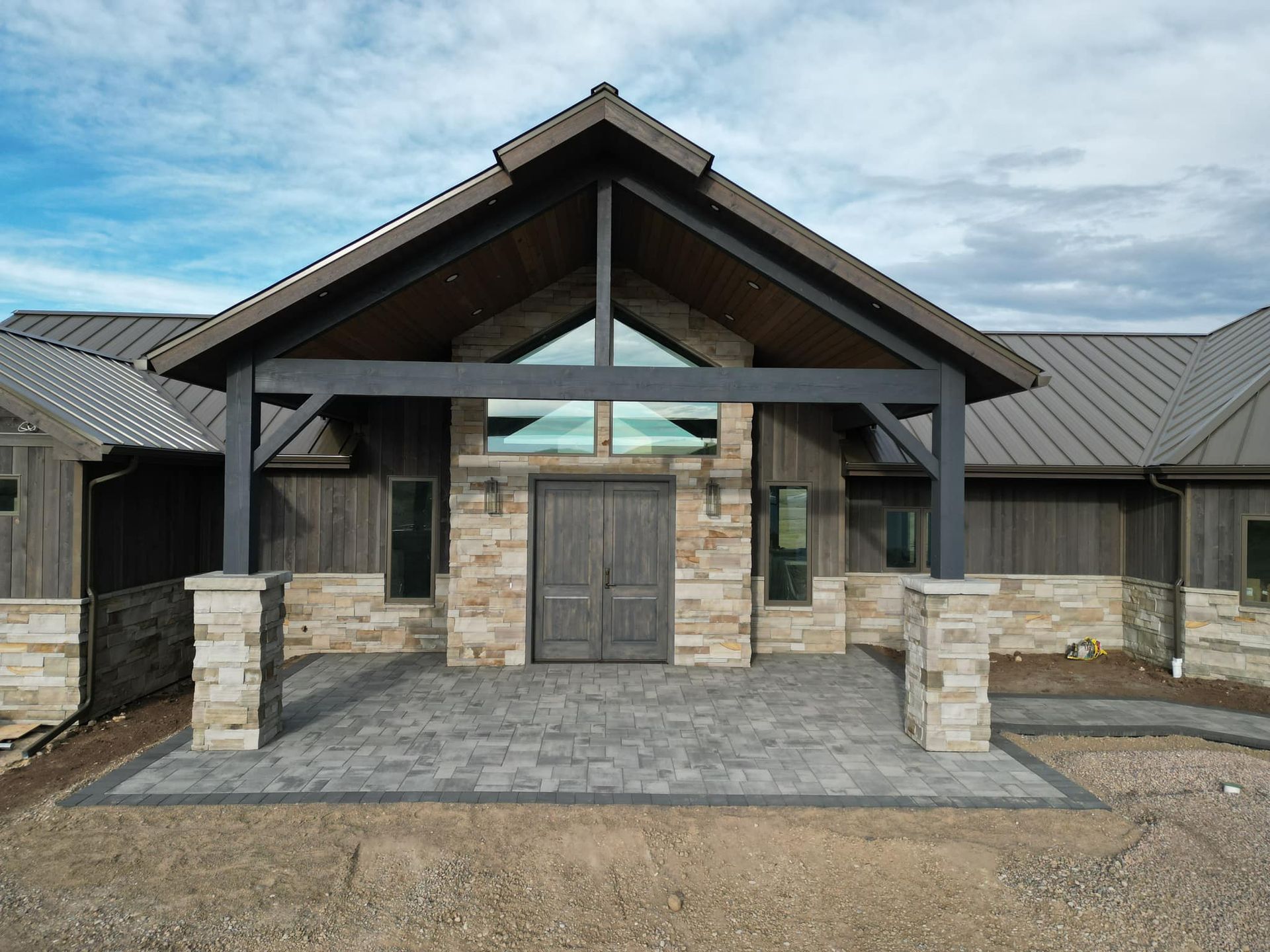 A large, stone-and-wood entrance to a building under a blue sky.