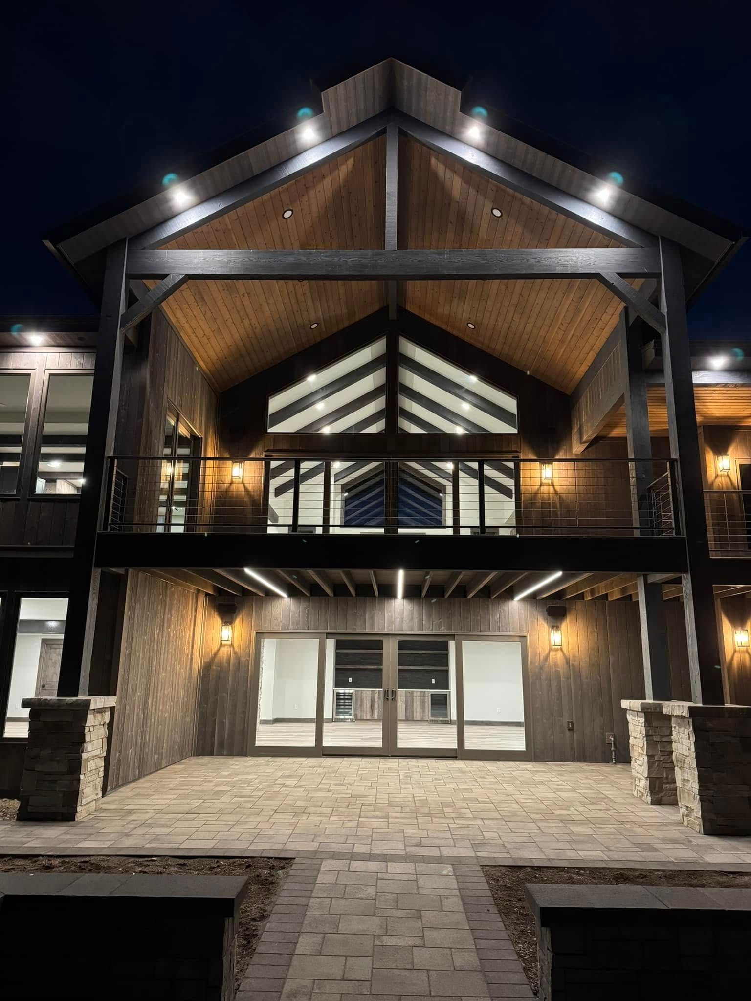 Night view of a two-story building with lit porch, stone exterior, and open doors.