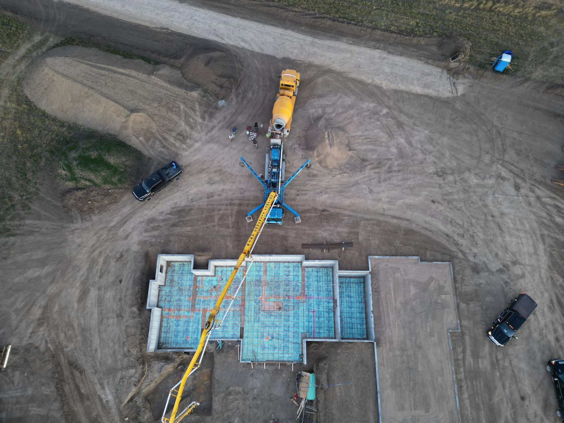 Construction site with a concrete pump pouring cement into a foundation.