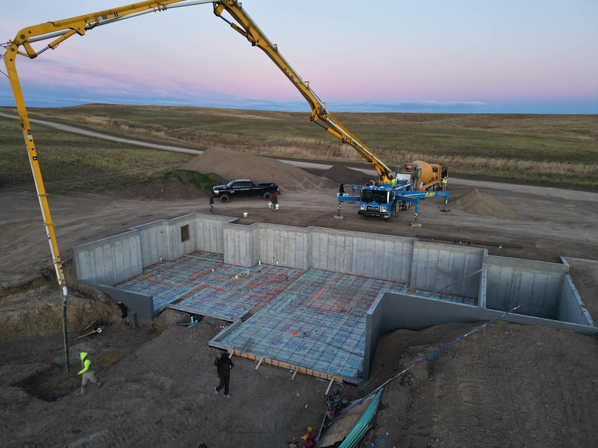 Construction site with a concrete pump truck pouring concrete into a foundation.