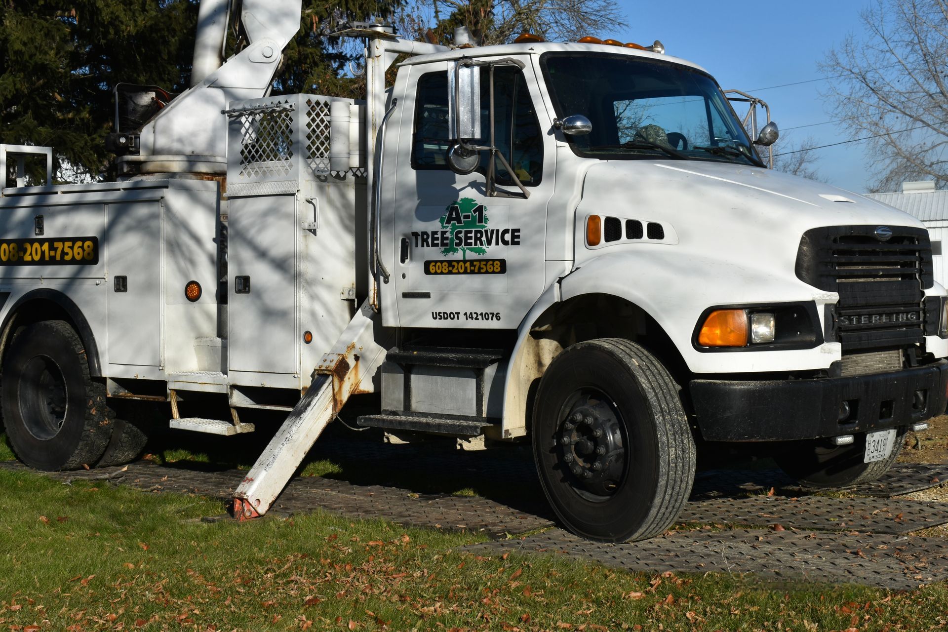 A white a1 Tree Service truck is parked in a grassy field.