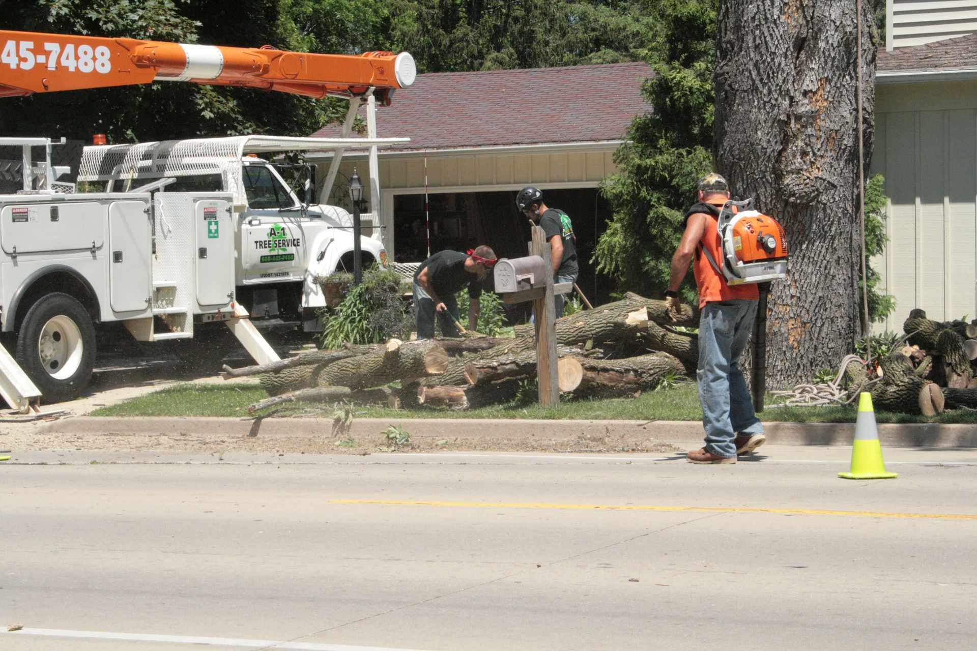 A1 Tree Service truck parked near a house. Servicemen are cleaning up after storm damage 
